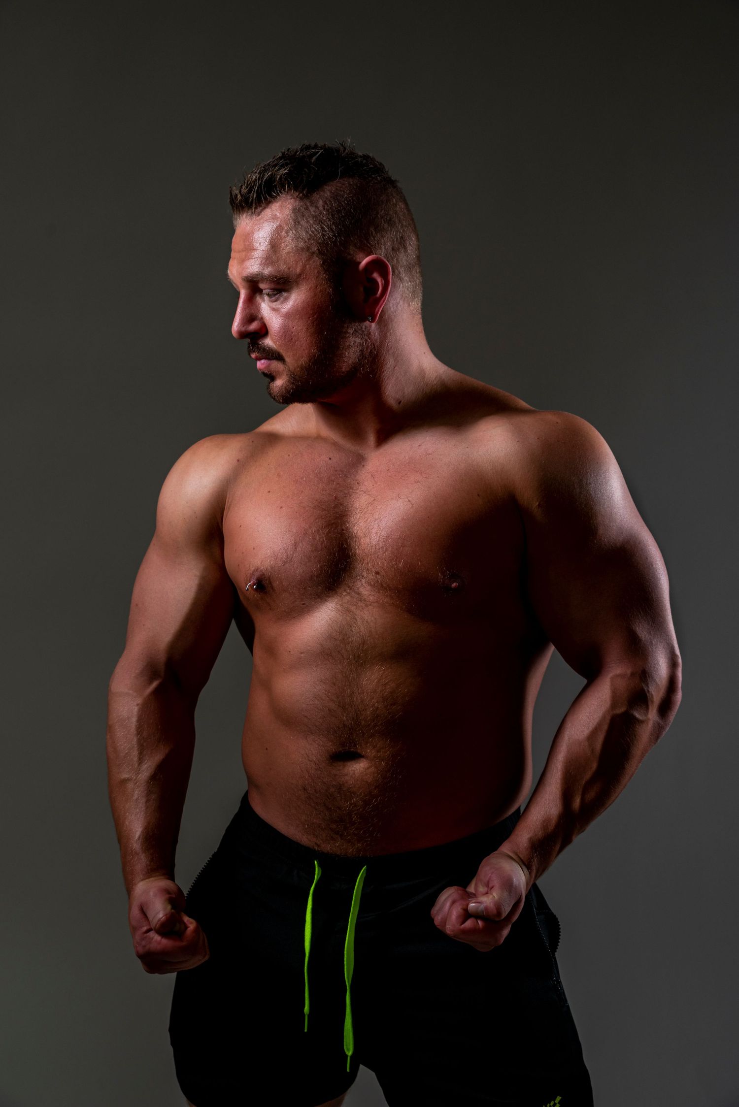 Athletic physique on display in dramatic studio lighting against dark background.