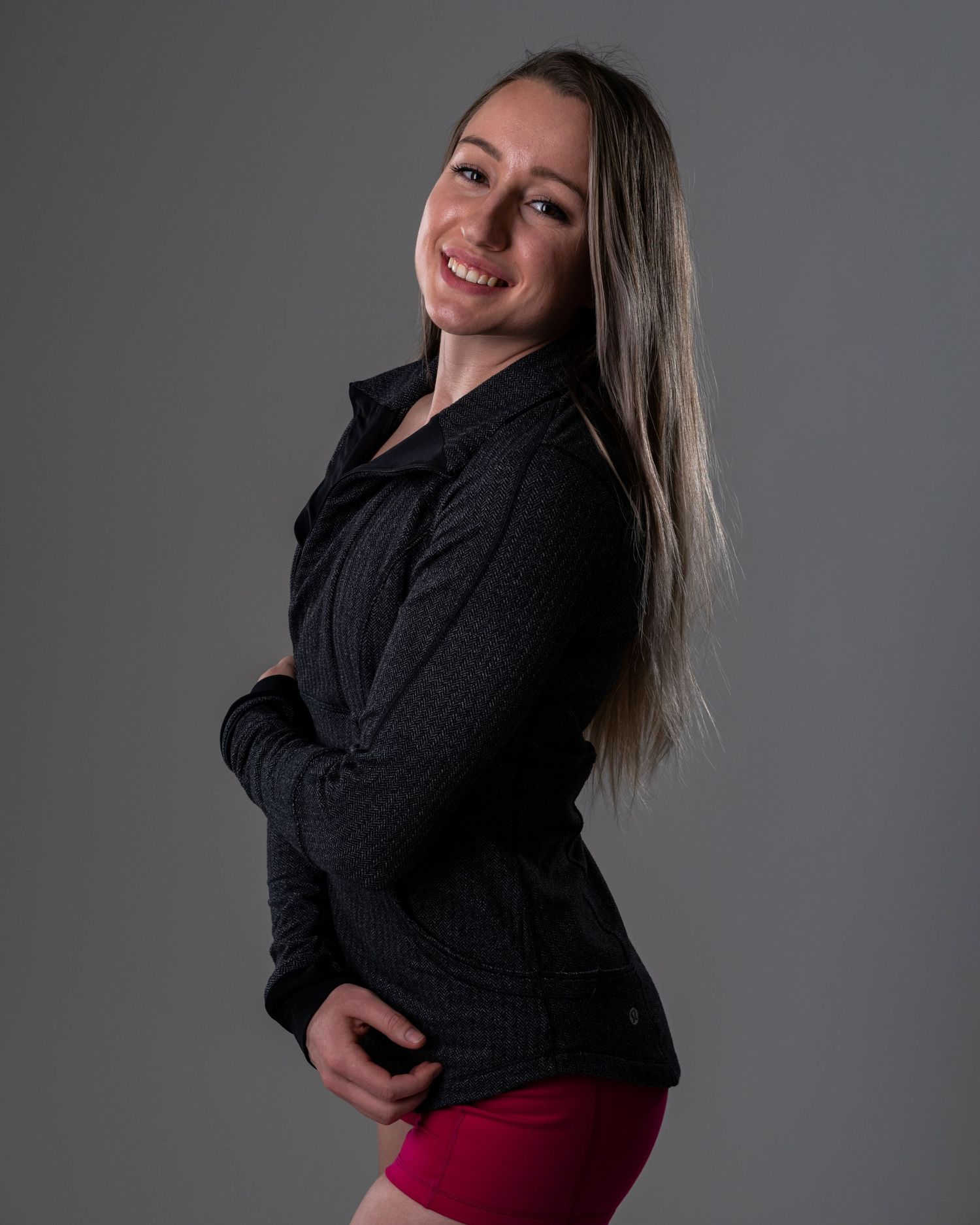 Studio portrait in black jacket against grey background.