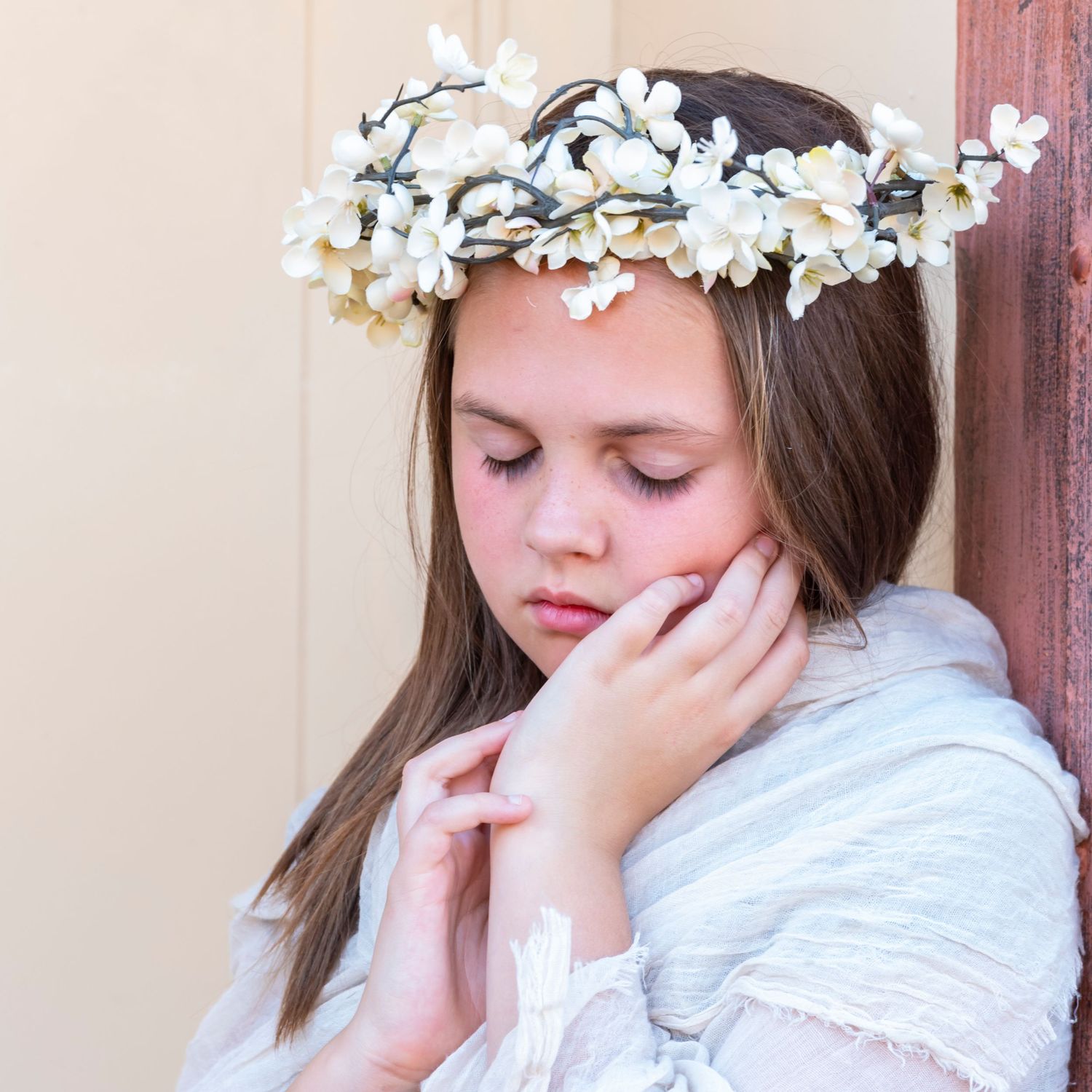 Dreamy portrait wearing white floral crown and delicate white dress.