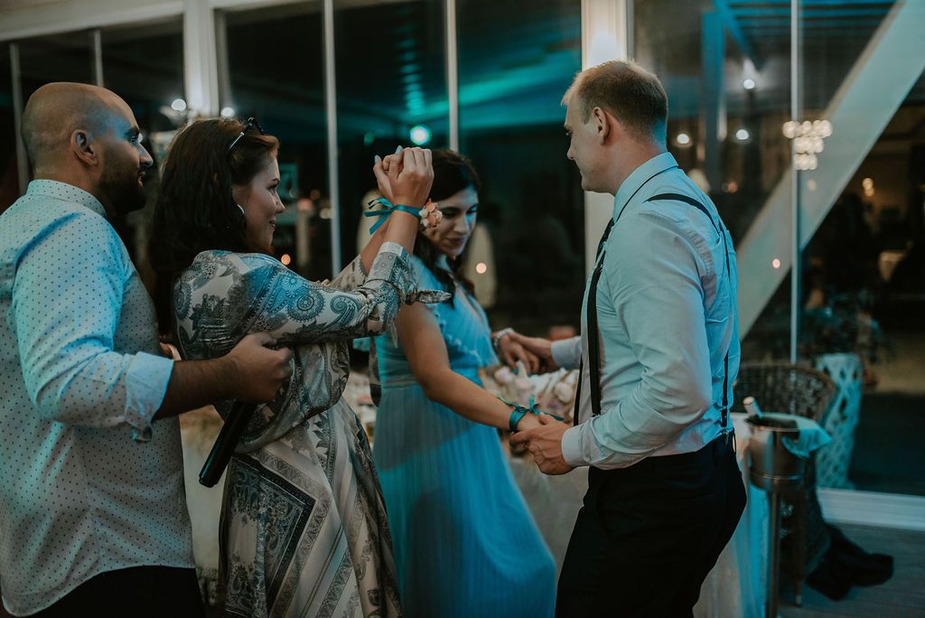 Guests enjoying a social gathering in an elegant venue with large windows and ambient lighting.