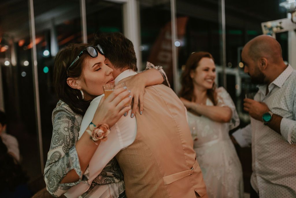 People embrace warmly during a dimly lit evening celebration.