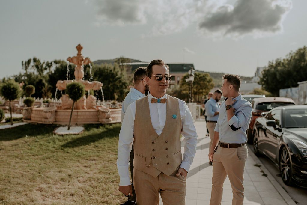 Wedding guests mingle outdoors at a beachside venue during golden hour.