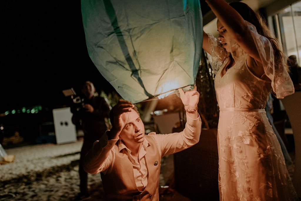 People preparing to release illuminated paper lanterns at a nighttime gathering.