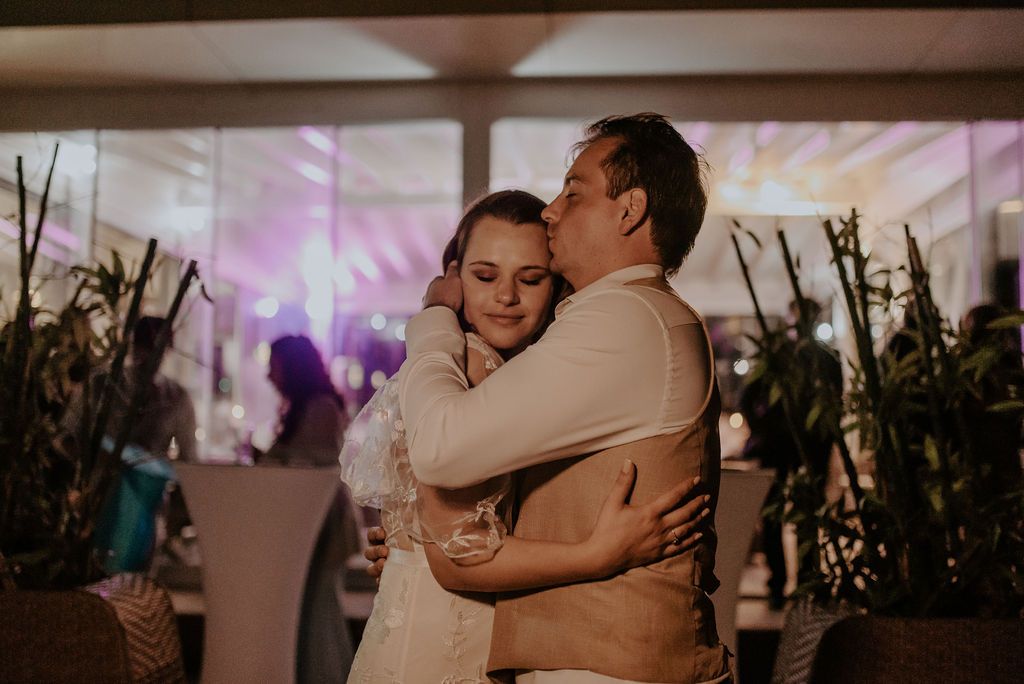 A couple shares an intimate dance moment in a decorated reception venue.