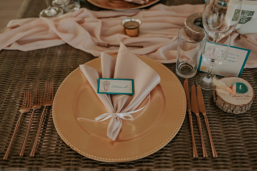 Elegant table settings with gold charger plates, white napkins, and teal accents at a formal event.