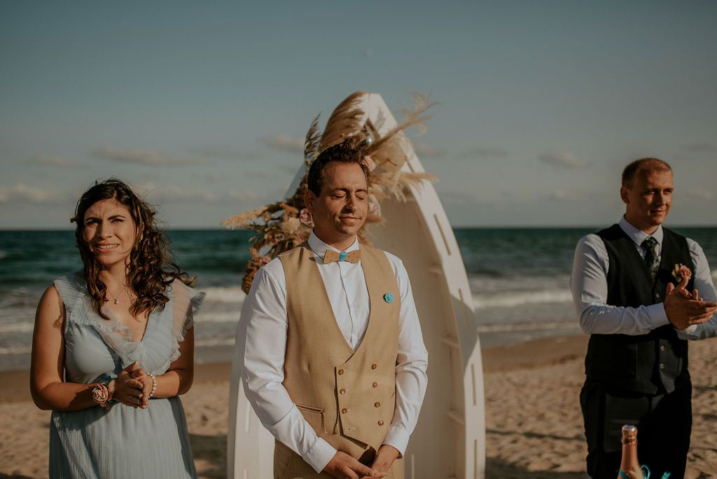 Intimate beach wedding ceremony with guests gathered near the ocean.