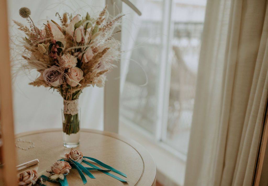 A delicate dried flower bouquet sits on a table near a window creating a romantic vintage atmosphere.