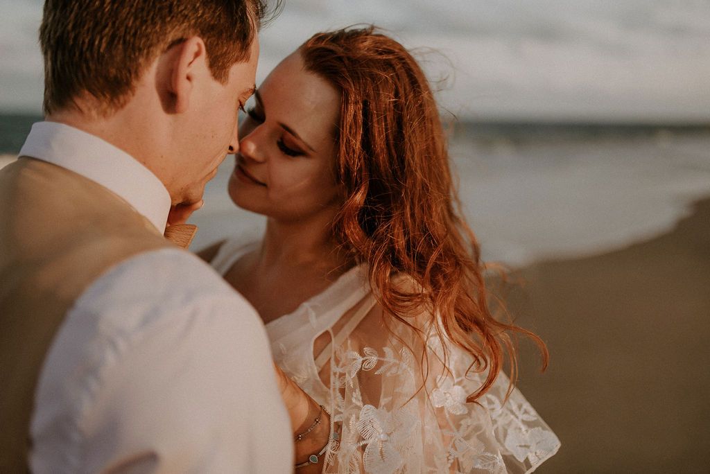 An intimate wedding portrait on the beach with soft lighting and ocean backdrop.
