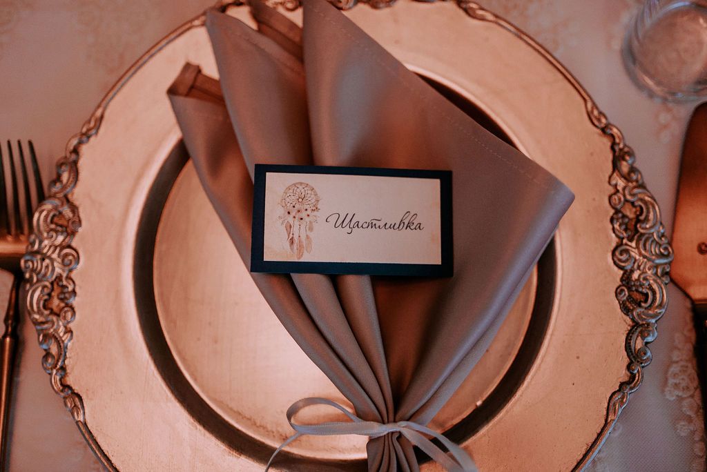Close-up of rose gold decorative plates and table settings at wedding reception.