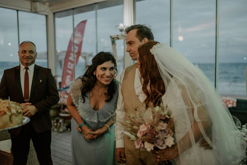 Candid moment of laughter during a seaside wedding reception.