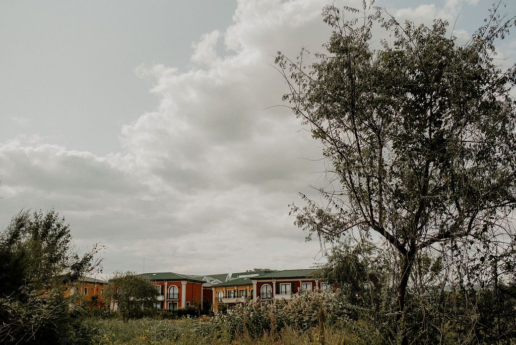 Modern buildings nestled among trees under a cloudy sky in a suburban landscape.