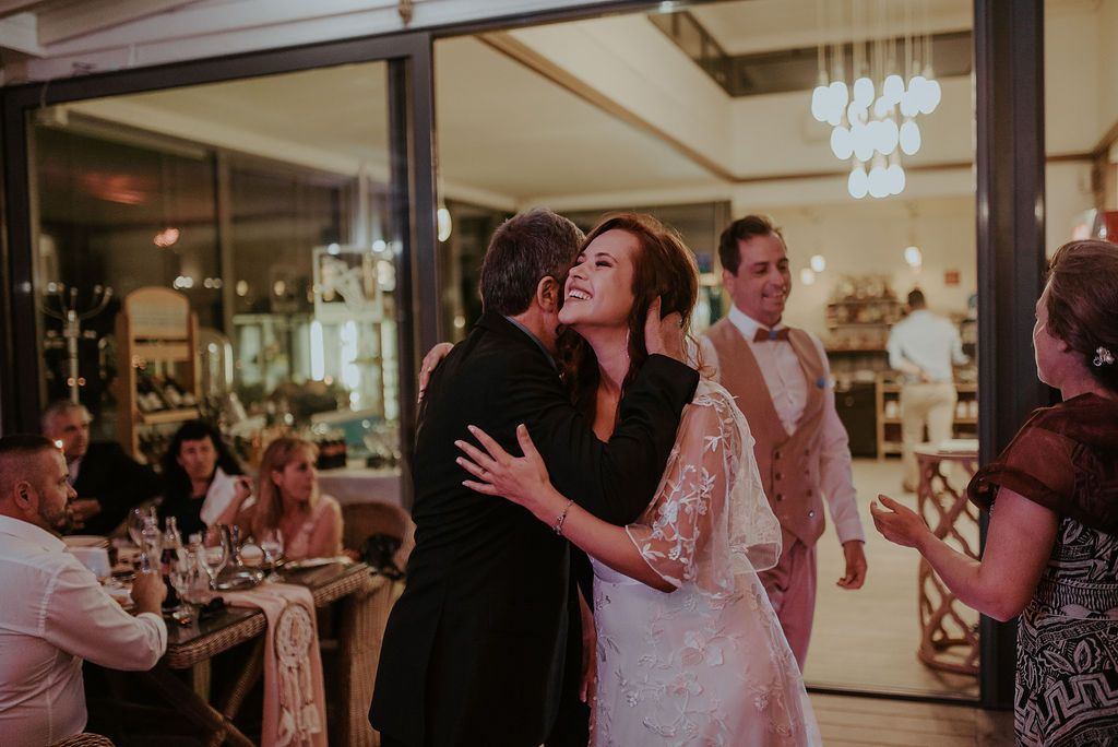 A joyful celebration during a wedding reception with guests dancing and embracing on the dance floor.