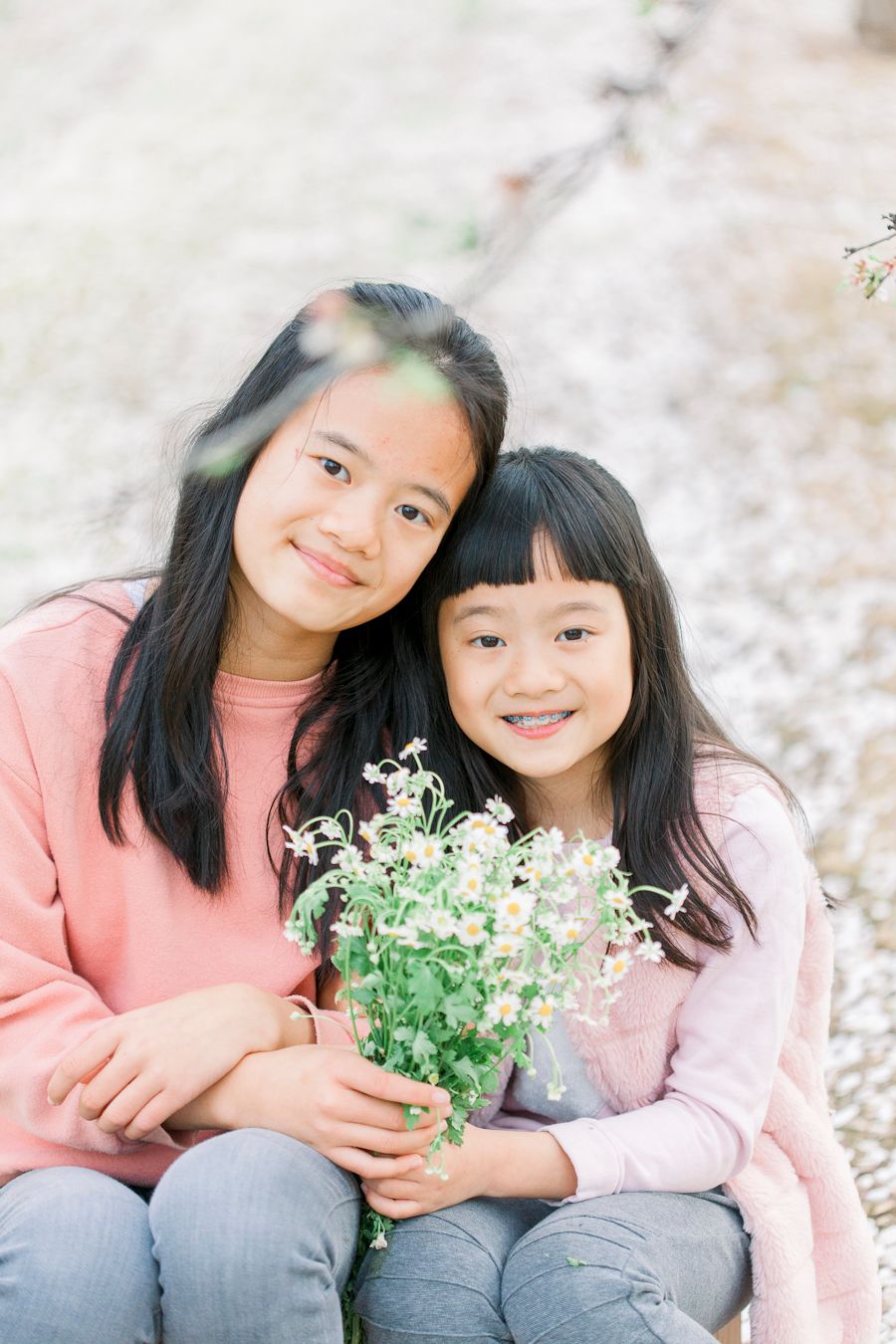 Two people sitting together holding small white flowers on a spring day.