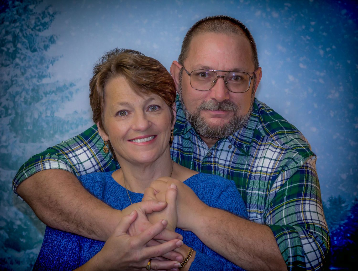 Studio portrait with blue backdrop and plaid shirt styling.