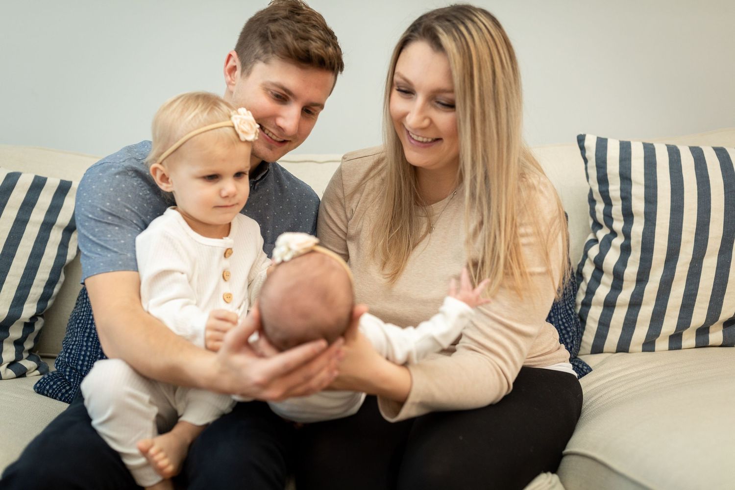 Family bonding with their toddler and newborn on a blue striped couch.