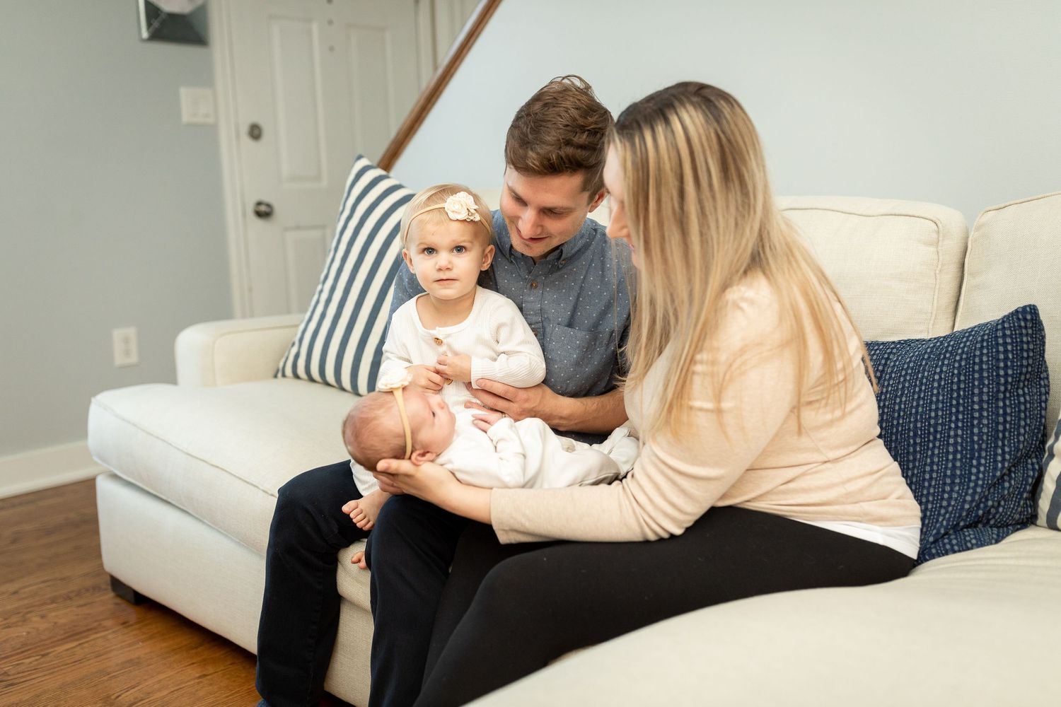 Family spending quality time with their babies on a beige couch.