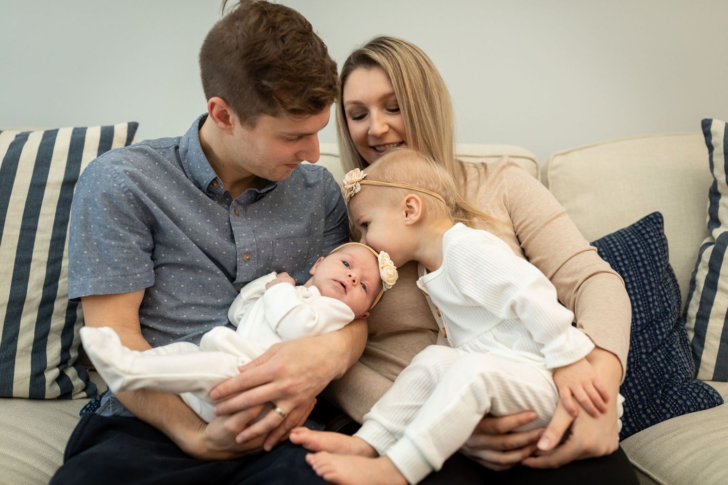 Parents share tender moment with their children on a couch.