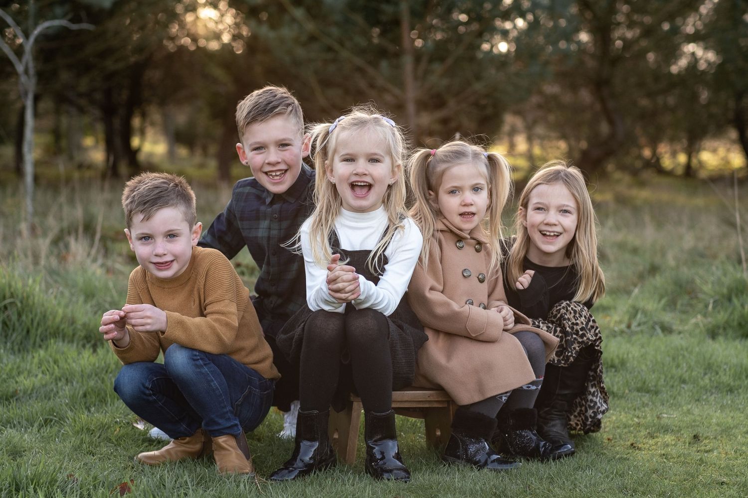 five children, all cousins, in beige clothes, witting in a field by wedding photographer aberdeen