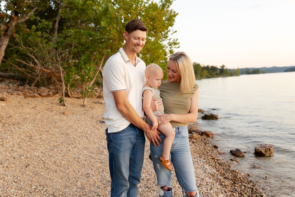 Couple shares romantic moments along a rocky beach shoreline at sunset.
