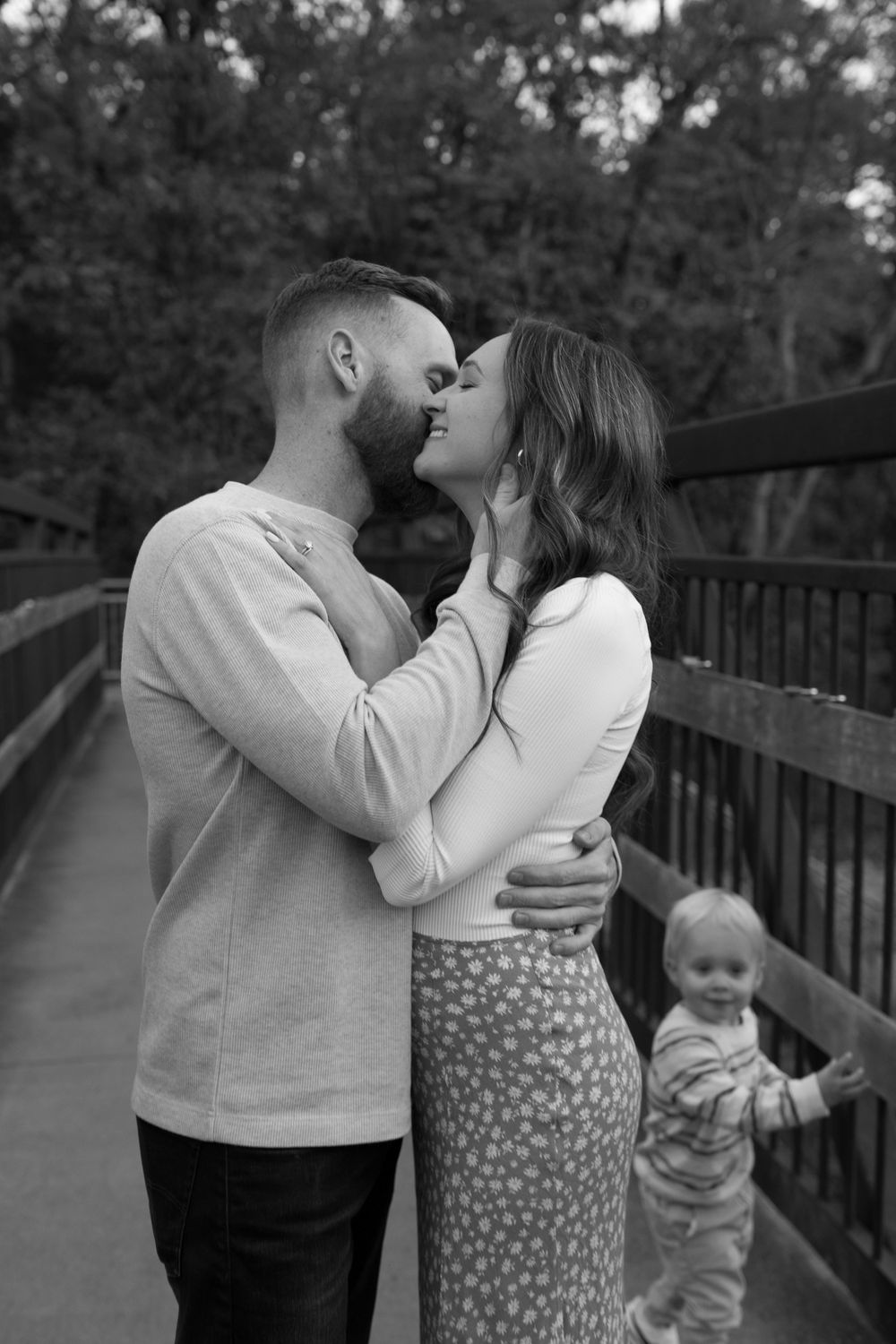 Intimate family moment captured on wooden bridge during fall season.