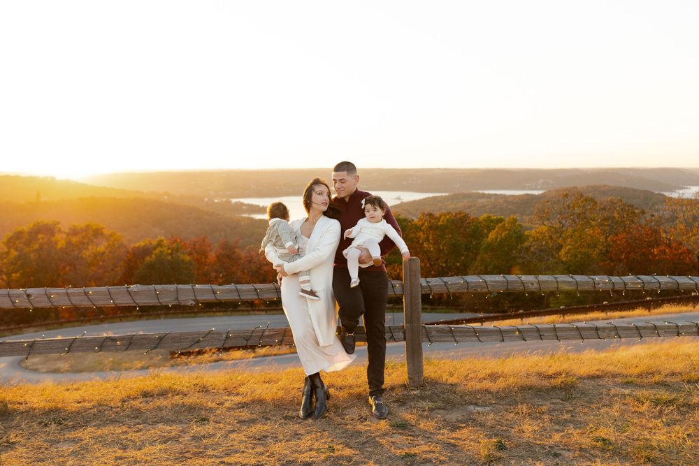Family enjoys playful moment together at sunset on hilltop.