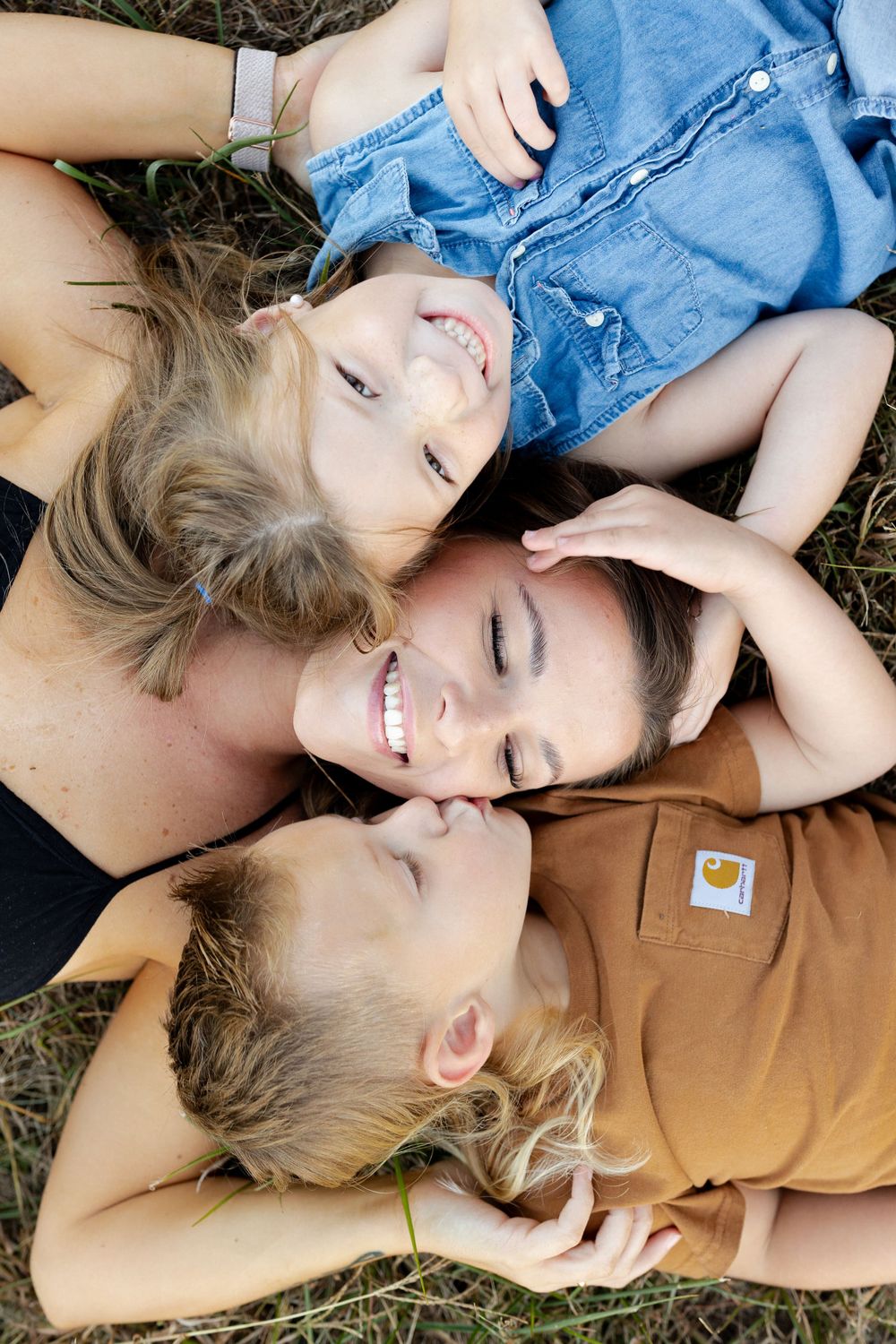 Overhead view of family lying in grass with heads together in circle formation.