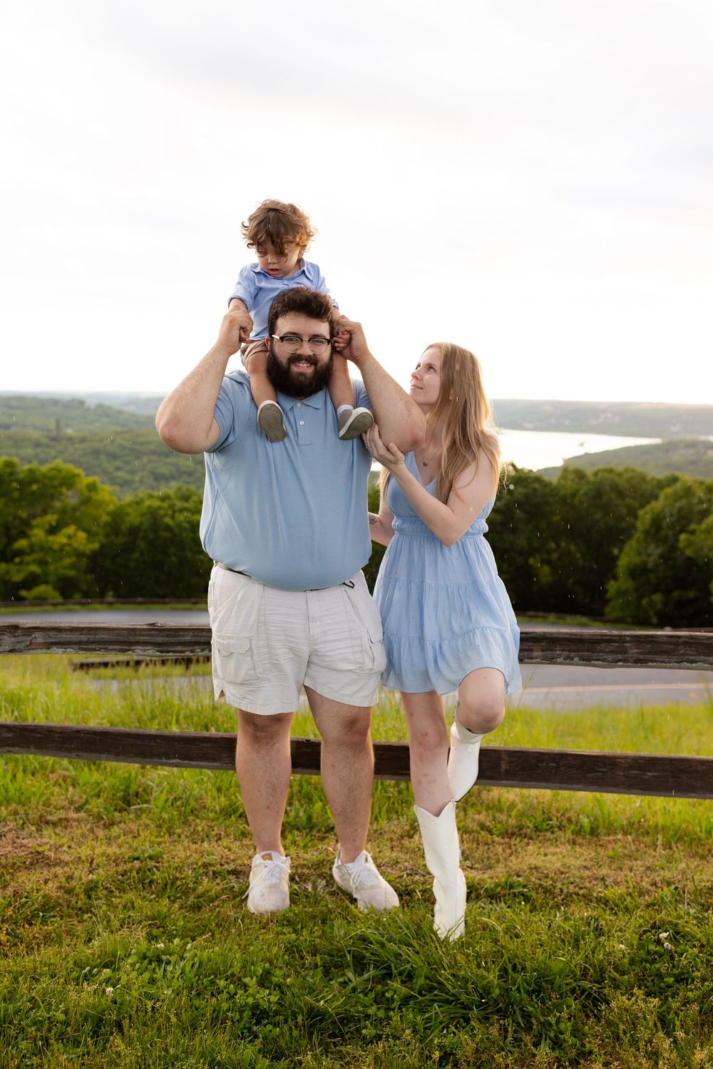 A family enjoys a summer day together on a grassy hilltop overlooking a scenic landscape.