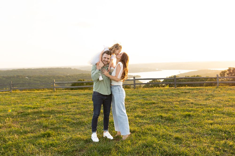 Couple enjoying tender moment on grassy hilltop at sunset.
