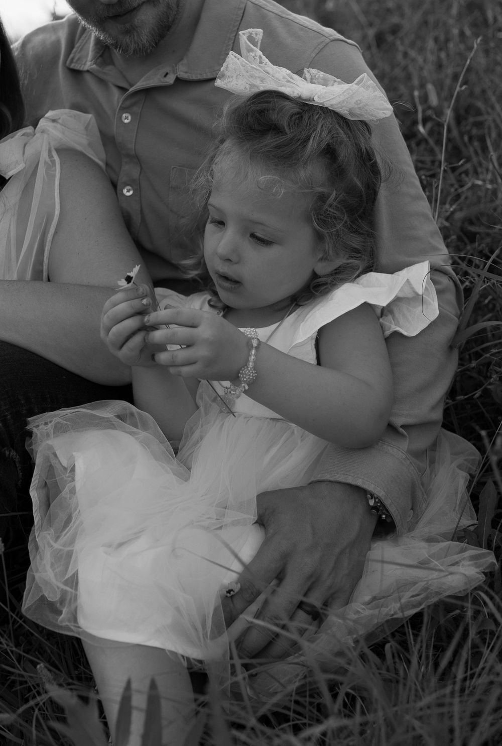 Black and white portrait of precious moment in field with white dress and bow.