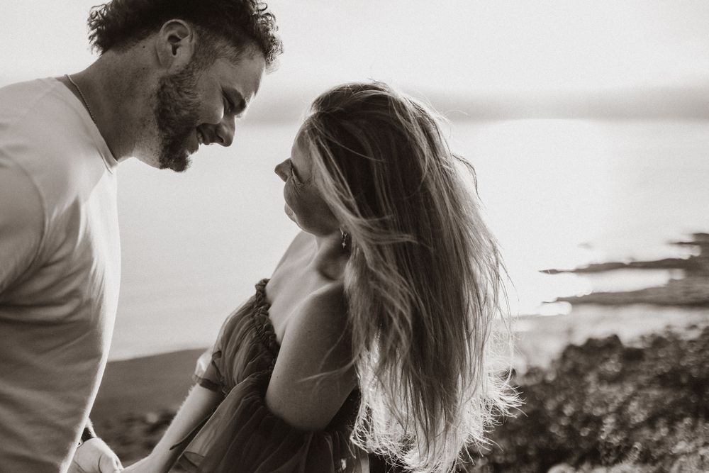 Black and white portrait of a couple in a tender embrace outdoors.
