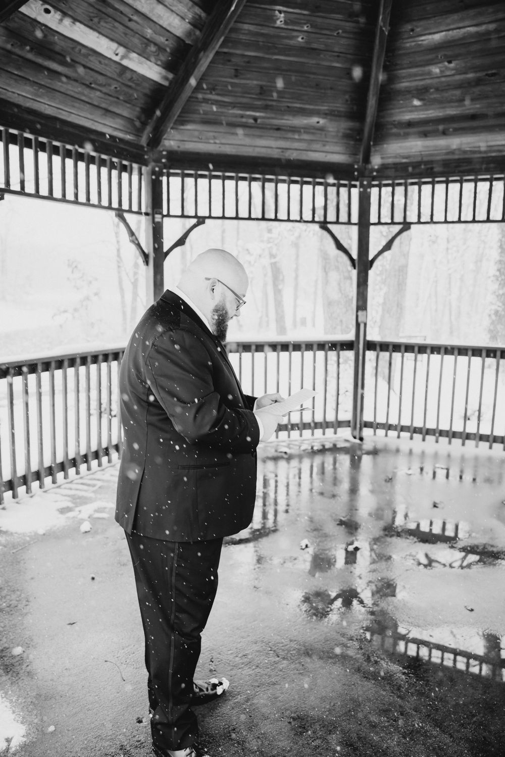 Black and white wedding photos in a gazebo during winter snowfall.