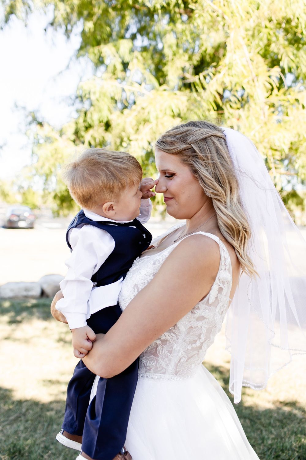 Tender moment captured outdoors under sunlit trees.