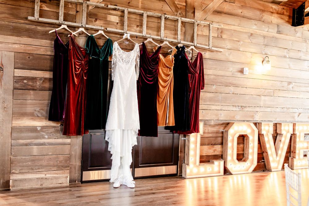Rustic barn venue interior with wooden walls and hanging wedding attire.