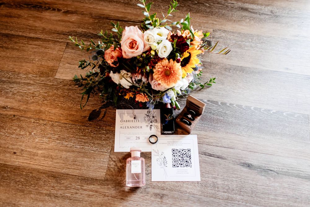 Wedding details including floral arrangements and paper goods displayed on a rustic wooden surface.