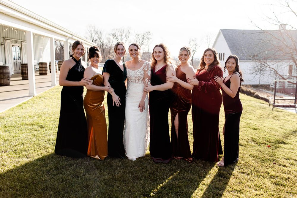 Wedding party in mixed burgundy and black attire posing together outdoors.
