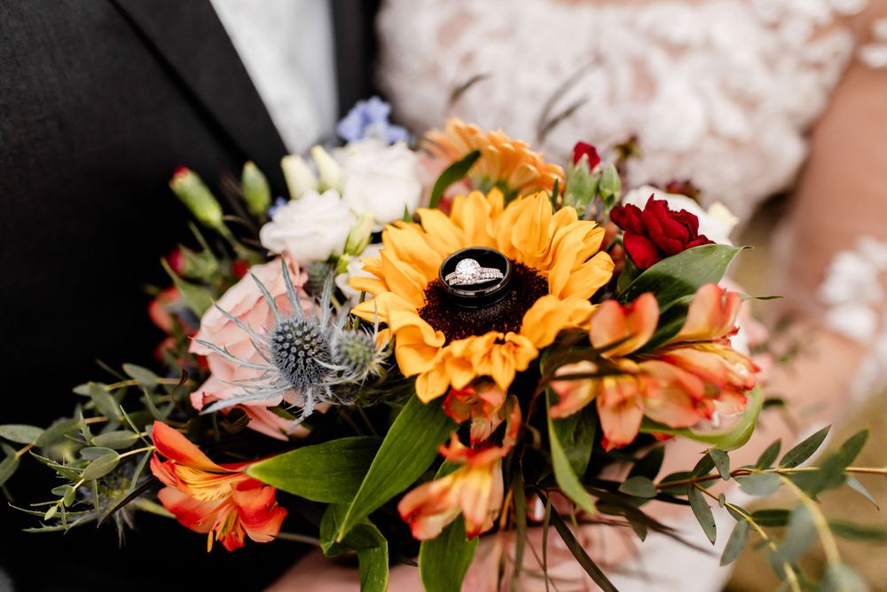 Vibrant wedding bouquet with sunflowers, orange blooms and greenery.