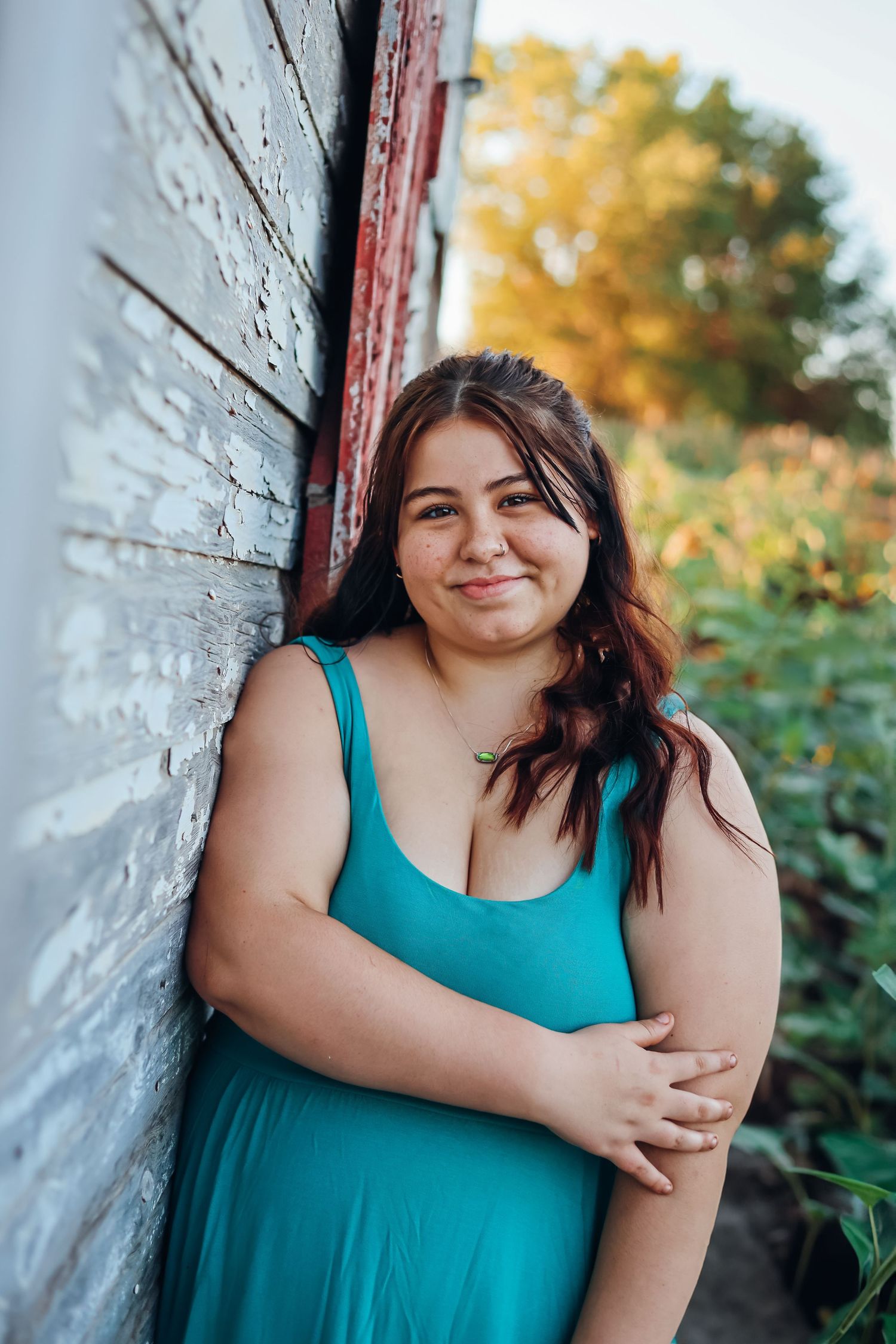 Series of outdoor portraits against a white wall with autumn foliage in the background. Senior photography