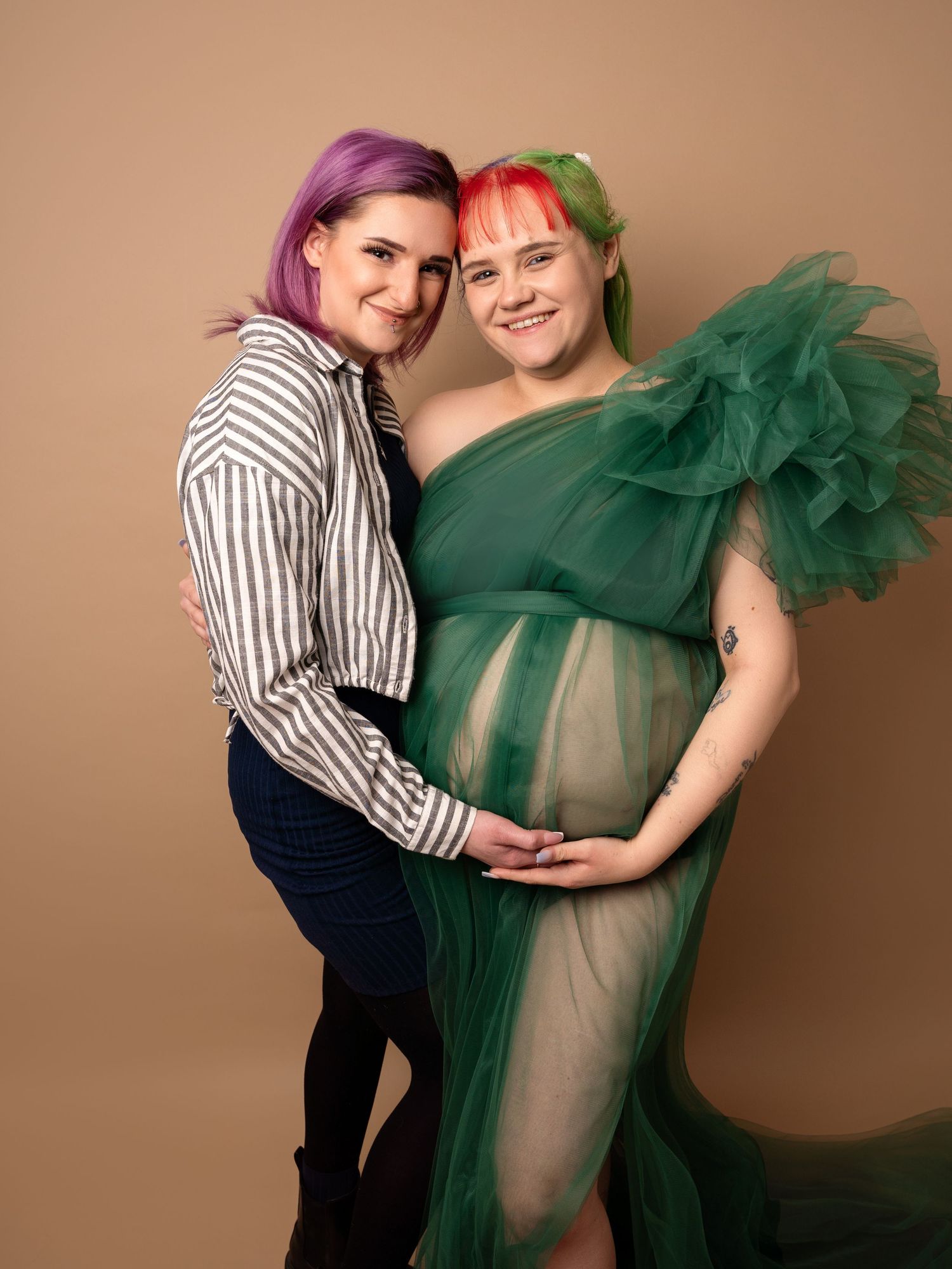 Pregnant lady in Beige tulle maternity gown holding bump, smiling at her maternity photoshoot in Doncaster.