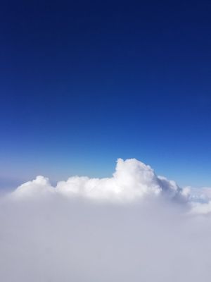 Aerial view of fluffy white cumulus clouds against a vivid deep blue sky taken from above.