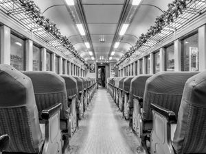 Black and white interior view of a vintage train car with rows of seats stretching toward the far end.