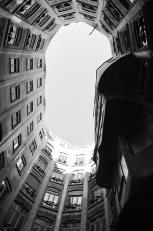 Black and white low angle view looking up through circular courtyard of historic building.
