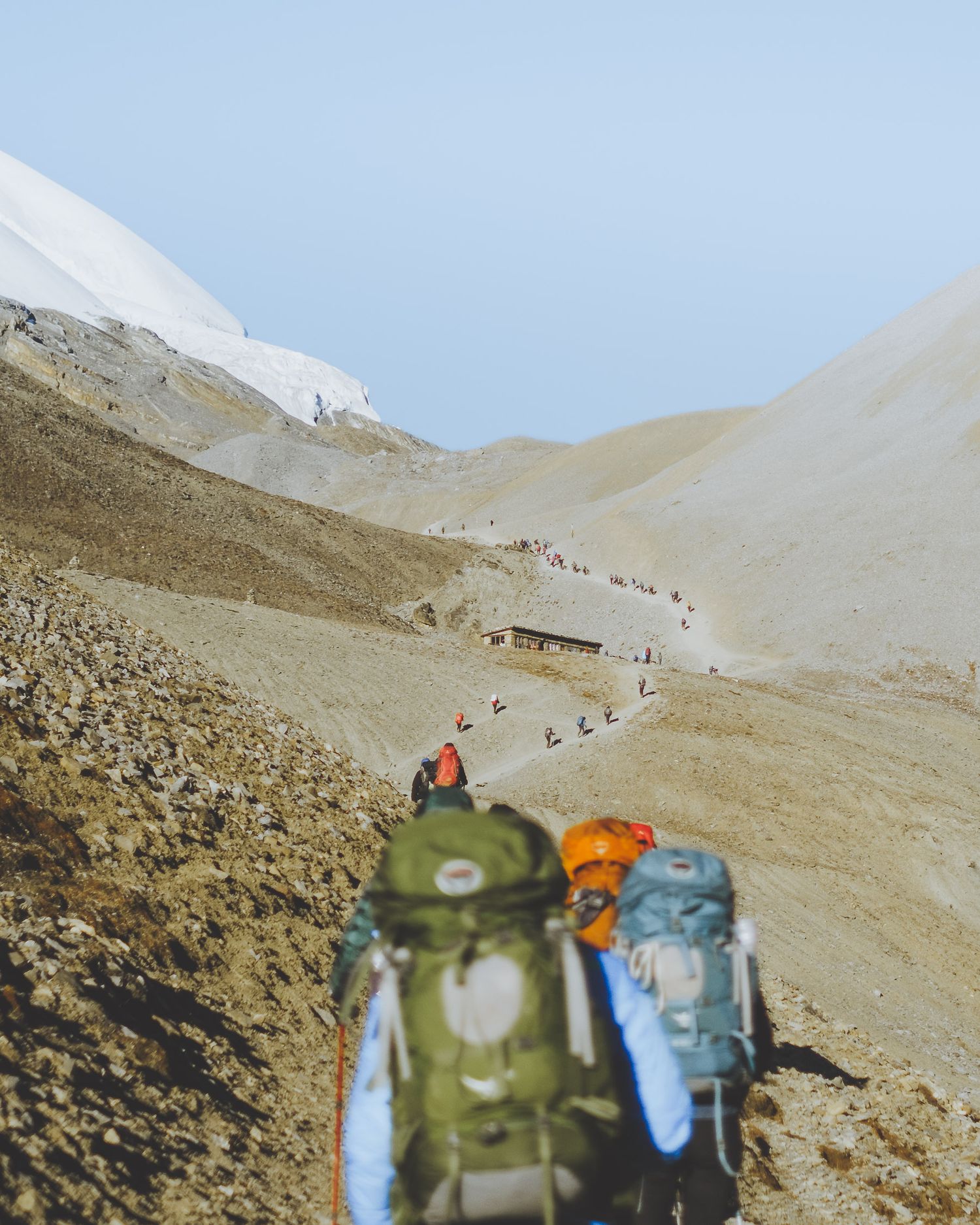 Hiking backpacks visible in foreground with mountainous trail stretching into distance.