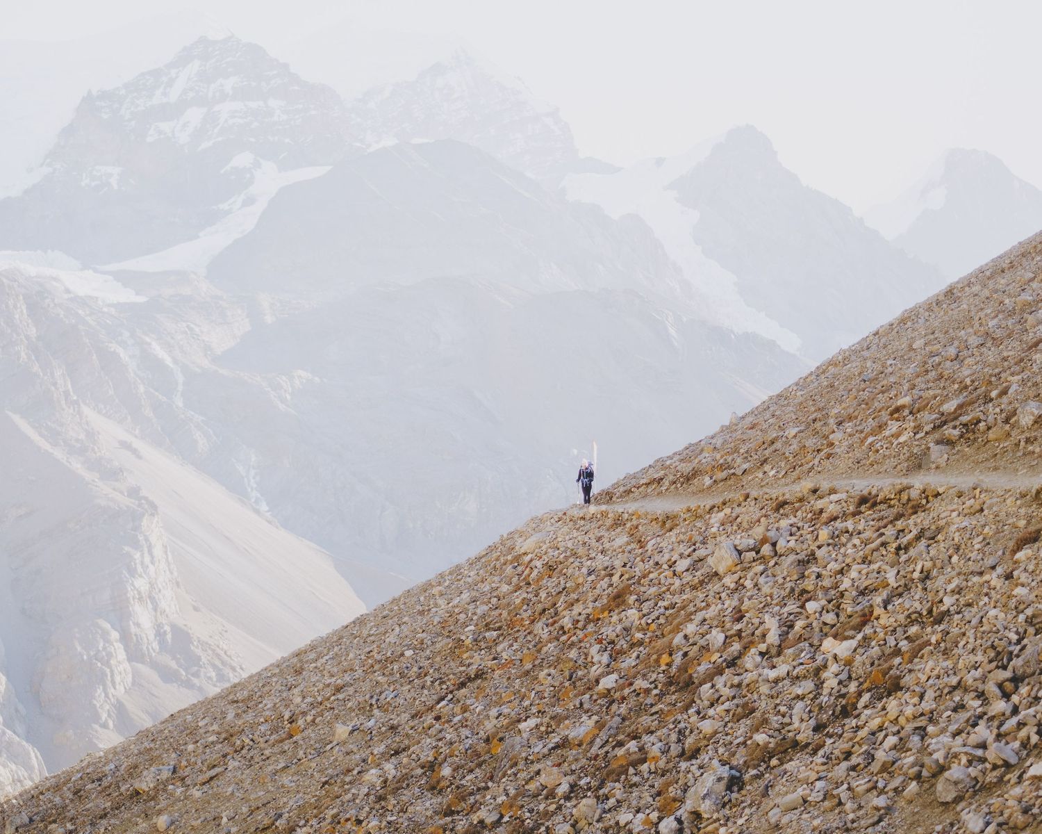 Distant view of snow-capped mountain peaks with rocky terrain in foreground.