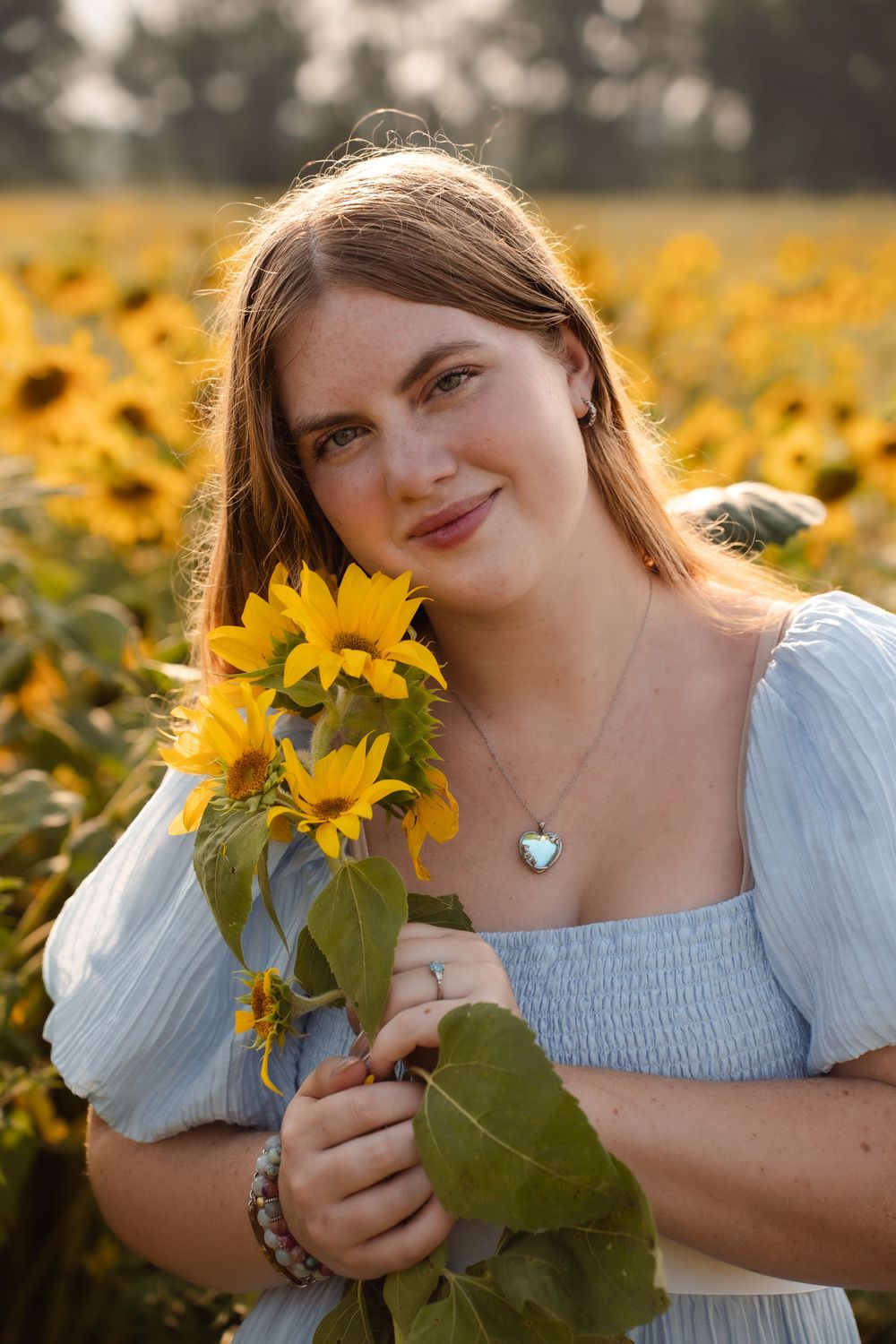 Sunflower field photoshoot featuring soft blue dress and golden afternoon lighting.