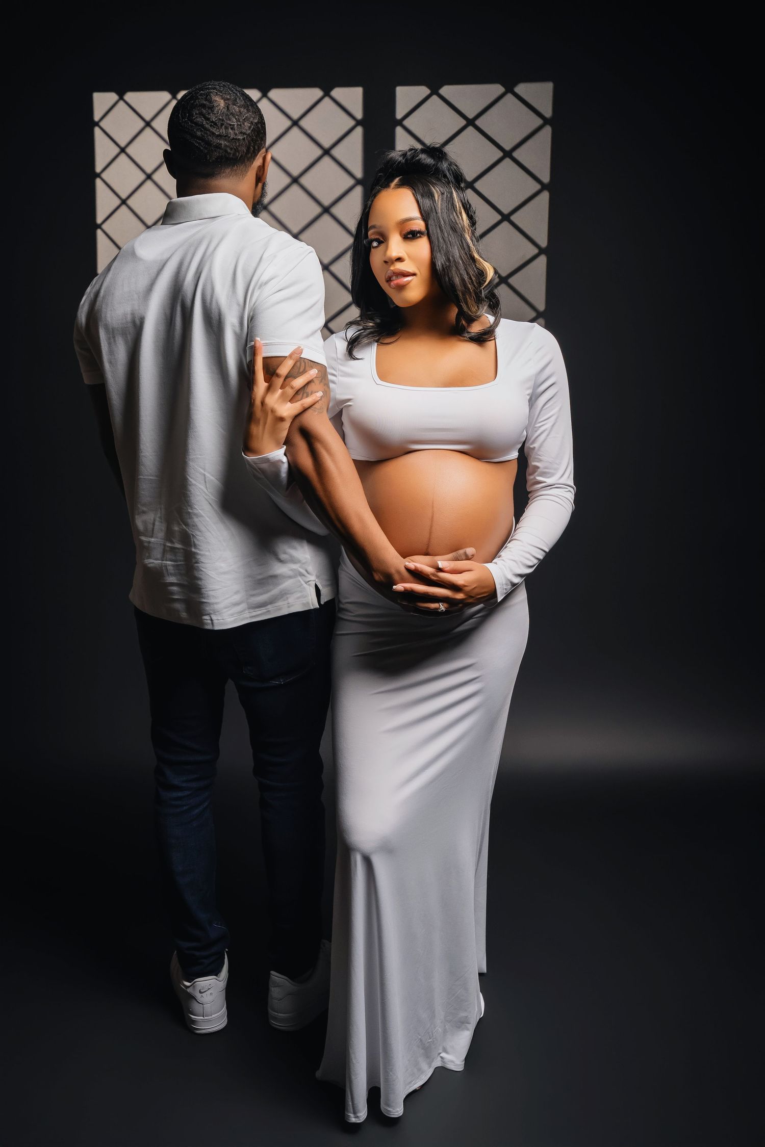 A dramatic maternity photoshoot with a couple in soft gray tones.