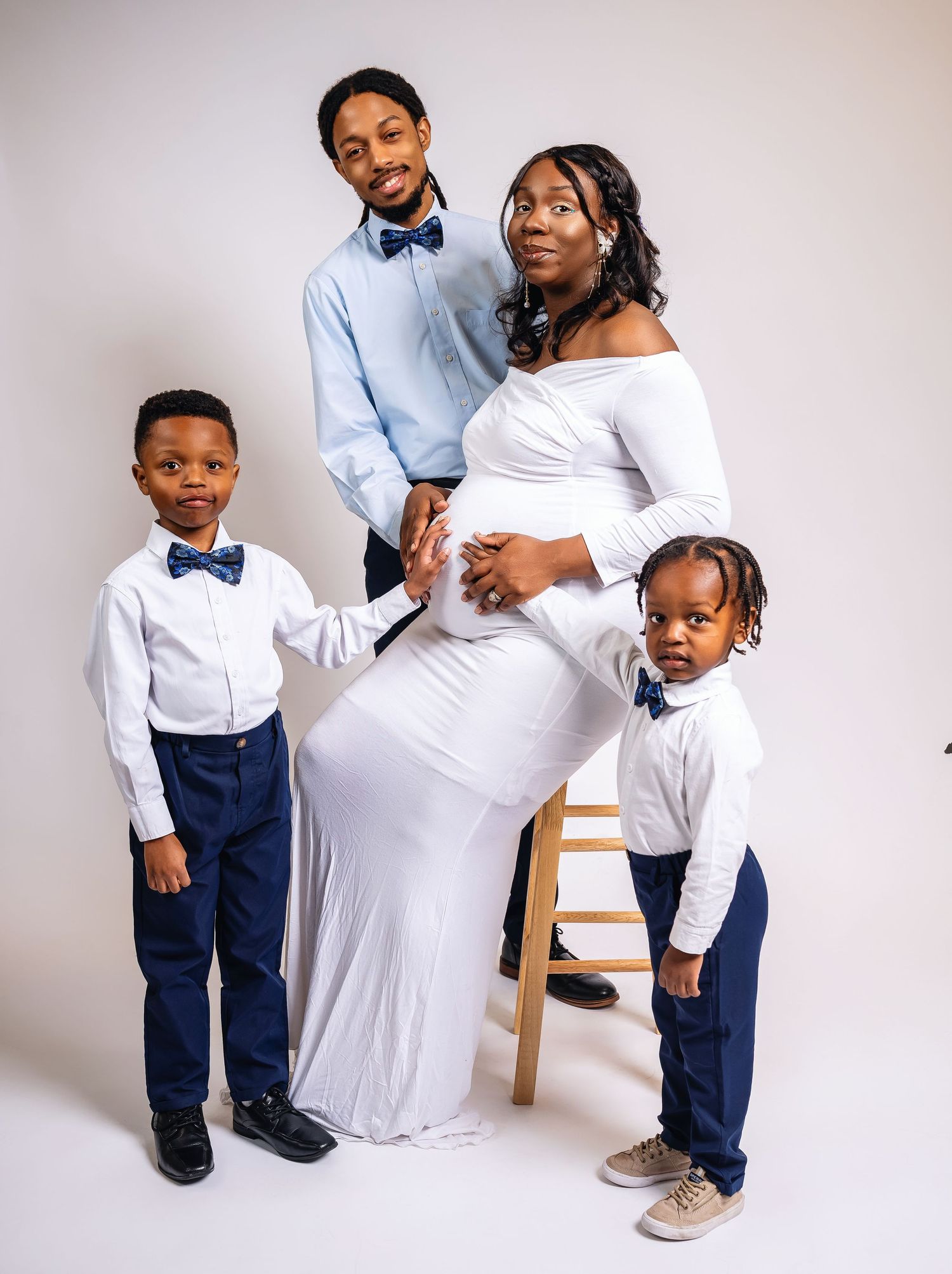 A formal family portrait with matching outfits against a white background.