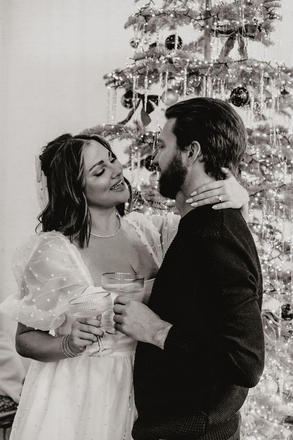 Couple sharing romantic moment in front of decorated Christmas tree.
