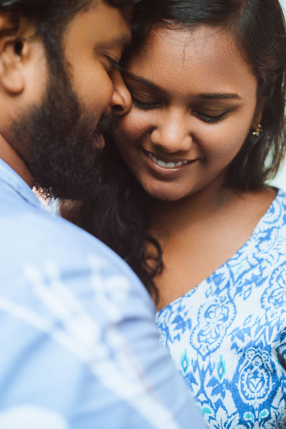 Intimate close-up of couple sharing a tender romantic moment while wearing blue clothing.