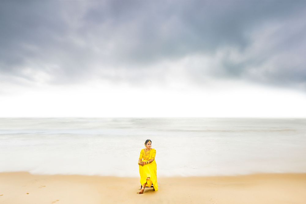 A person in a bright yellow dress stands alone on a misty beach.