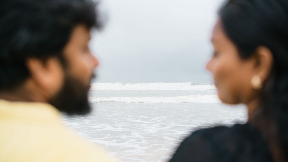 Silhouetted couple looking at each other against an ocean backdrop.